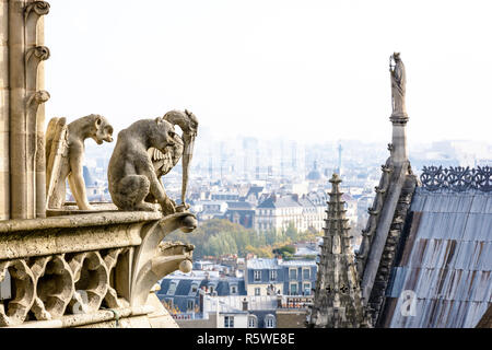 Drei Statuen von Chimären mit Blick auf das Dach der Kathedrale Notre-Dame und dem historischen Zentrum von Paris von den Türmen Galerie mit der Stadt Stockfoto