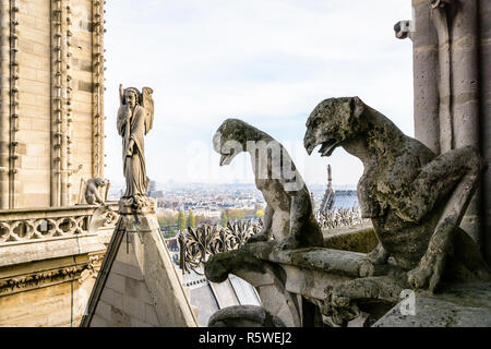 Zwei steinerne Statuen von Chimären mit Blick auf das Dach der Kathedrale Notre-Dame de Paris von den Türmen Galerie mit der Statue von einem Engel mit trumpe Stockfoto