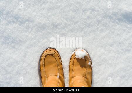 Die Beine der Frauen in Stiefeln im Schnee, Winter kommt, Hallo Winter, kopieren Raum oben, Ansicht von oben. Stockfoto