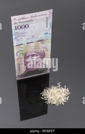 Hyperinflation Konzept - Venezolanische Bolivar Fuerte (Typ) mit Lebensmittel (Reis Körner) - Metapher eine galoppierende Inflation in Venezuela & Geld wertlos. Stockfoto