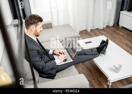 Elegante Geschäftsmann im Anzug arbeiten mit Laptop auf der Couch zu Hause oder Büro bequem gekleidet Stockfoto