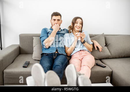Junges Paar mit Angst Emotionen Fernsehen sitzen zusammen auf der Couch zu Hause Stockfoto