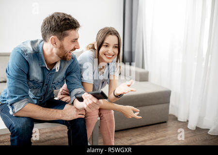 Junge paar schöne mit glücklichen Gefühle Fernsehen sitzen zusammen auf dem Tisch zu Hause Stockfoto