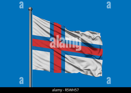 Flagge der Färöer Inseln im Wind gegen den tiefblauen Himmel. Stockfoto