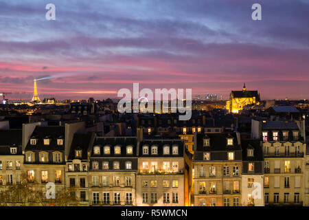 Blick auf Paris mit klassischer Architektur in Abend mit leuchtenden Fenstern und Eiffelturm beleuchtet in der Nacht während Rosa und Lila Sonnenuntergang Stockfoto