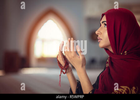 Junge betende Frau, die auf Knien in die Moschee Stockfoto