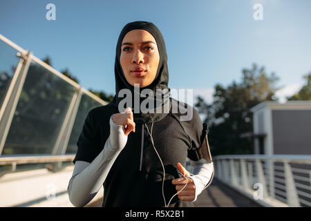 Gesunde sportliche Frau, tragen, hijab Joggen im Freien in der Stadt. Die islamische Frau in den frühen Morgenstunden ausgeführt wird. Stockfoto