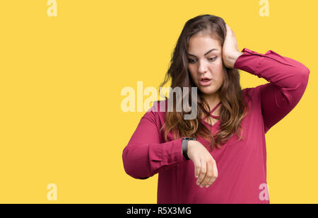 Schöne Übergrößen junge Frau über isolierte Hintergrund ein Blick auf die Uhr Zeit Sorgen, Angst, sich spät Stockfoto