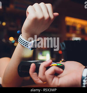 Zugeschnittenes Bild der weiblichen Kunden zahlen über Smart Watch an der Bar Stockfoto