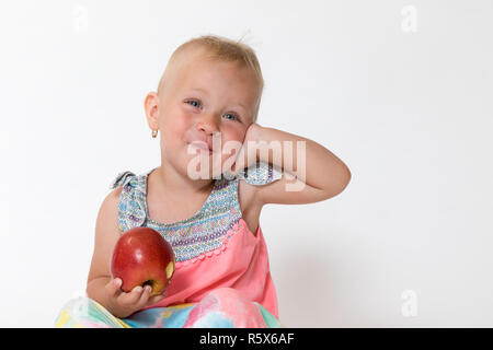Smilling kleinkind Mädchen sitzt und hält roten Apfel Stockfoto