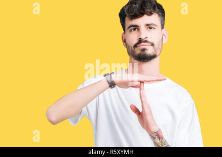 Jungen gutaussehenden Mann tragen weiße T-Shirt über isolierte Hintergrund tun time out Geste mit den Händen, frustriert und ernstes Gesicht Stockfoto