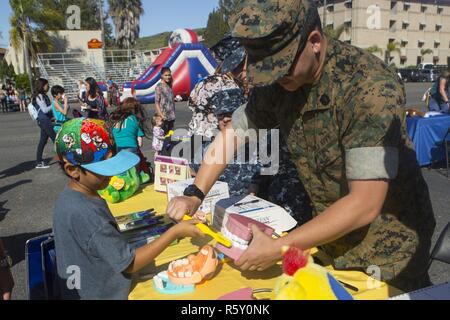 US-Marine Sohn Bürsten der Zähne eines Mund-Displays mit Hilfe der Seemann Patrick Deguzman, Zahntechniker mit 1. Dental Bataillon während der 1. Marine Logistics Group Eggstravaganza am 22 Bereich Parade Deck auf der Marine Corps Base Camp Pendleton, Kalifornien, 13. April 2017. Das Display dient, die Marines, Segler sowie ihre Kinder, die eine visuelle Darstellung dessen, was zu ihrem Mund geschehen kann, wenn angemessene Hygiene nicht verwendet wird und die Vorteile der Verwendung der richtigen Hygiene zu geben. Stockfoto