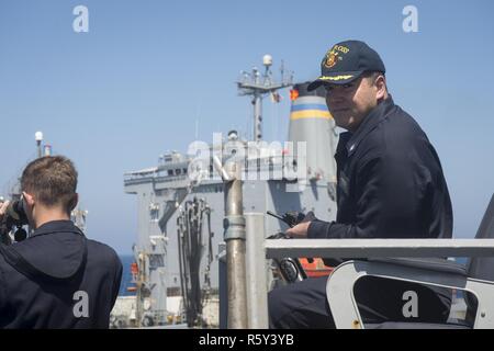 Mittelmeer (15. April 2017) Cmdr. Bryan Gallo, kommandierender Offizier der USS Ross (DDG71), beobachtet eine Auffüllung-auf-See mit dem Militär Sealift Command flotte Auffüllung öler USNS Joshua Humphreys (T-AO 188) April 15, 2017. USS Ross, einer der Arleigh-Burke-Klasse geführte-missile Destroyer, Vorwärts - Rota, Spanien bereitgestellt werden, ist die Durchführung von naval Operations in den USA 6 Flotte Bereich der Maßnahmen zur Unterstützung der US-amerikanischen nationalen Sicherheitsinteressen in Europa und Afrika. Stockfoto