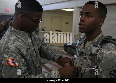 US Army Spc. Khalil Jenkins, links, ein US-Soldat zugewiesen 982nd Combat Camera Company, prüft ein Fallschirm-Geschirr, US Army Spc. Darius Davis, ausserdem die 982nd Combat Camera Company angehören, während Fallschirm Ausbildung Operationen an Papst Army Airfield befindet sich in Fort Bragg, NC, 21. April 2017. US-Soldaten, die 982nd Combat Camera Company, 824th Quartermaster Company und der United States Army Civil Affairs und Psychological Operations Command zugewiesen anschickten für einen Fallschirmsprung aus einem c-130 Hercules, die Flugzeuge auf Sizilien-Drop-Zone befindet sich in für Stockfoto