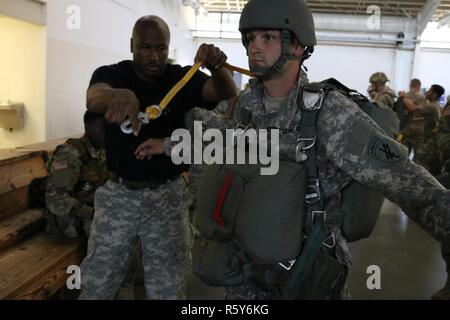 US Army Chief Warrant Officer John Harris, links, ein Heli zugewiesen 824th Quartermaster Company, inspiziert die statische-Line zur US Armee Sgt. Jason Starkweather, rechts, zugewiesen, die United States Civil Affairs und Psychological Operations Command, während Fallschirm Ausbildung Operationen an Papst Army Airfield befindet sich in Fort Bragg, NC, 21. April 2017. US-Soldaten, die 982nd Combat Camera Company, 824th Quartermaster Company und der United States Army Civil Affairs und Psychological Operations Command zugewiesen bereiteten für einen Fallschirmsprung aus einer c-130 Stockfoto