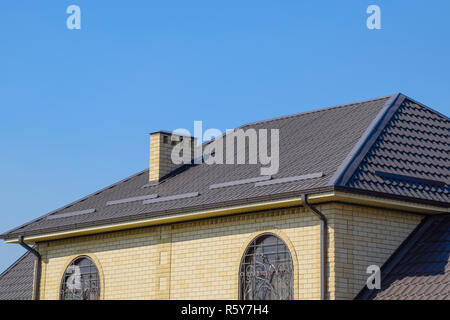 Haus der Yellow Brick und braune Wellpappe Dach aus Metall. Gitter an den Fenstern. Stockfoto