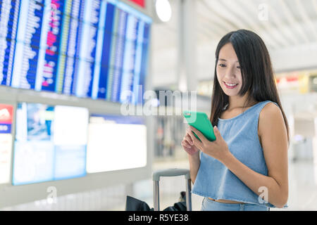 Frau mit Handy ihr Flugplan zu prüfen. Stockfoto