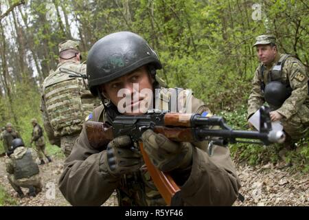 Eine ukrainische Soldaten und Student an der Yavoriv Bekämpfung von Training Center Beobachter Controller Trainer Akademie bietet Sicherheit während einer situativen Übung an der Yavoriv CTC auf der internationalen Friedens und der Sicherheit, in der Nähe der Yavoriv, der Ukraine, der am 20. April. Akademie Studenten nahmen die Umdrehungen, die Ülg und wurden von ukrainischen und US-Soldaten auf die Gemeinsame Multinationale Ausbildung Gruppe - Ukraine zugeordnet betreut. Die JMTG-U Mission ist es zu helfen, die Fähigkeiten des CTC und Professionalität in der Ukrainischen Militär bauen. Stockfoto