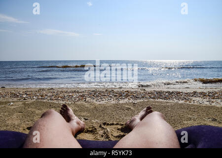 Die Beine von einem Mann auf einem Strand Hintergrund. Ein Mann liegt auf einem amatra Stockfoto