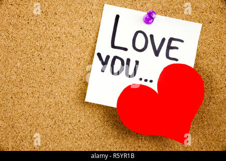 Eine gelbe Haftnotiz schreiben, caption, Beschriftung Phrase LIEBE DICH... in Schwarz ext auf einem weißen Haftnotiz zu einem Kork Pinnwand angeheftet Stockfoto