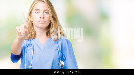 Schöne junge Arzt Frau mit medizinischen gleichmäßig über isolierte Hintergrund zeigt mit dem Finger auf und verärgerten Ausdruck Stockfoto