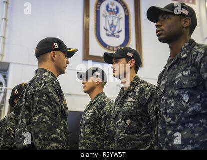 Pazifik (21. April 2017) USS Makin Island befehlshabenden Offizier, Kapitän Mark A. Melson, Links, spricht mit Feuer Controlman 2. Klasse Briley Dixon, von Sioux City, Iowa, während eine Teilanmeldung einheitliche Inspektion im Hangar Bucht des Amphibious Assault Ship. Makin Island, das Flaggschiff der Makin Island amphibischen bereit, mit der begonnen 11 Marine Expeditionary Unit, arbeitet in der Indo-Asia-pazifischen Region amphibische Fähigkeit mit regionalen Partnern zu verbessern und als gebrauchsfertige Response Force für jede Art der Kontingenz zu dienen. Stockfoto