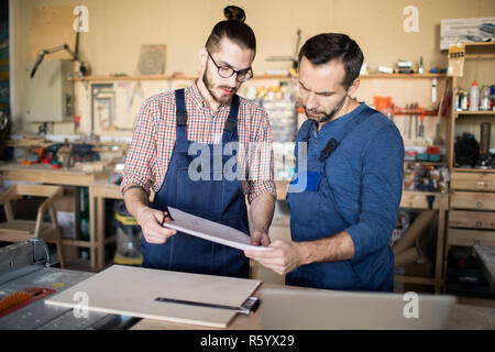 Taille bis Portrait von zwei modernen Zimmerleute auf Pläne, bei Arbeiten in der Schreinerei Werkstatt, Platz kopieren Stockfoto