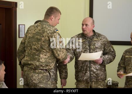 Ukrainische Oberstleutnant Pavlo Rozhko, der Kommandant der Yavoriv Combat Training Center, präsentiert ein Absolvent des CTC Beobachter Controller Trainer Akademie mit einem Zertifikat während einer Diplomverleihung an der CTC auf der internationalen Friedens und der Sicherheit, in der Nähe der Yavoriv, der Ukraine, der am 25. April. Stockfoto