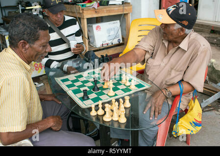 Afro-Männer spielen Schach außerhalb einer Nähmaschine Reparaturwerkstatt. Täglichen Lebensstil in Cartagena de Indias, Kolumbien. Okt 2018 Stockfoto