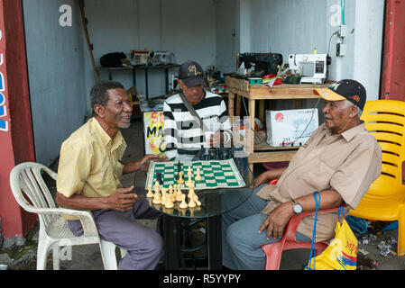 Ältere Männer Schach spielen außerhalb einer Nähmaschine Reparaturwerkstatt. Das tägliche Leben in Cartagena de Indias, Kolumbien. Okt 2018 Stockfoto