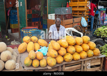 Afro-Mann verkauf Papaya auf lokaler Bazurto Markt. Cartagena de Indias, Bolívar, Kolumbien. Umwelt portrait. Okt 2018 Stockfoto