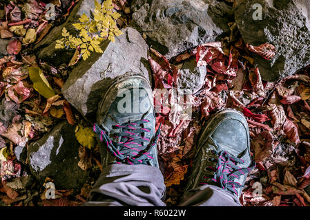 Blick von oben auf die Verfolgung Schuhe mit Stein und gelbe und rote Blätter im Herbst Park gefallen, Herbst Szene. Kopieren Sie Platz Stockfoto