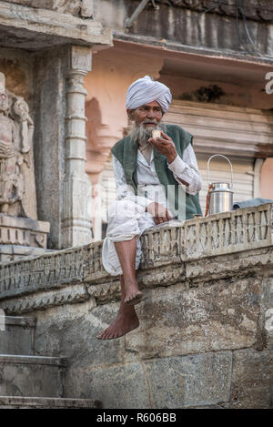 Ein alter Mann trinkt Tee vor einem hindu-Tempel, Udaipur, Rajasthan, Indien Stockfoto
