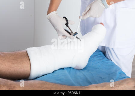 Arzt binden Verband am Fuß der Person Stockfoto