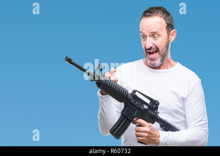 Mittleres Alter senior hoary kriminellen Mann mit Pistole Waffe über isolierte Hintergrund sehr glücklich zeigte mit Hand und Finger Stockfoto