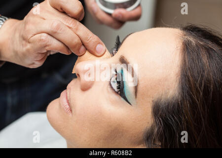 Make-up-Artist, die Stiftung mit einem Schwamm, der zu einer weißen Frau Stockfoto