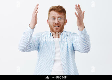 Verzweifelt umgekippt Kerl auf seine Lieblingsspieler, sehr große Fehler, Gefühl enttäuscht und schockiert, stehend über graue Wand mit erhöhtem h worred Stockfoto