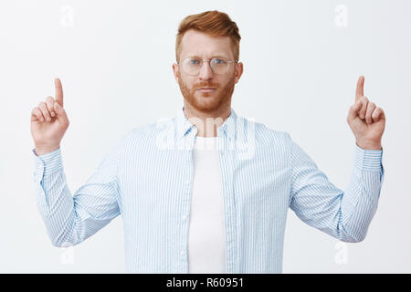 Up team Hören, fordern unser Einkommen zweimal zu erheben. Gut aussehende ernst und smart Geschäftsmann mit roten Haaren in Gläsern und Shirt, heben Zeigefinger Stockfoto