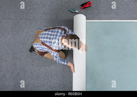 Junge männliche Arbeiter in Overalls Rolling Teppich Stockfoto