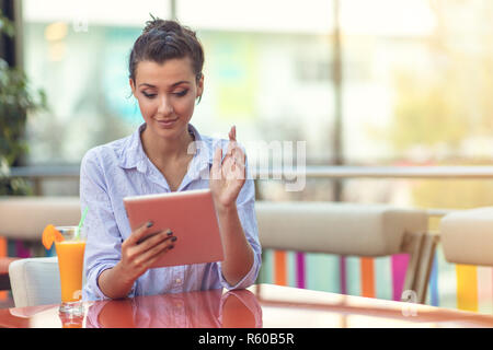 Schönen gemischten Rasse Frau mit einem afro Frisur Holding eine digitale Tablet im Coffee Shop Stockfoto