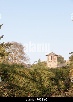 Alte Stein Turm im Abstand im Himmel hinter Hedge Tree Tops Stockfoto