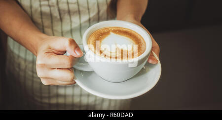 Close-up Hand einer Kellnerin, um eine Tasse Kaffee zu Kunden dienen. Stockfoto