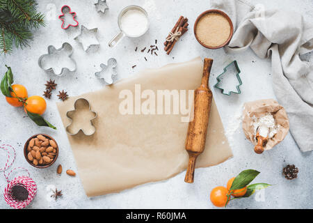 Weihnachten Backen Konzept. Ausstechformen, Nudelholz, Backpapier und Zutaten auf Concete Hintergrund. Ansicht von oben Lebkuchen Kekse backen. Kopieren S Stockfoto