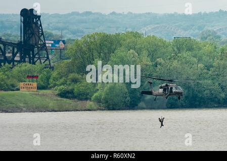 Ein Kentucky Army National Guard UH-60 Blackhawk Hebezeuge Flieger von 123 Speziellen die Kentucky Air Guard Taktiken Squadron in das Flugzeug nach Durchführung einer simulierten Rescue Mission in den Ohio River in Louisville, Ky., 22. April 2017. Die Demonstration war Teil des Donners über Louisville, eine jährliche Air Show, zieht Tausende von Zuschauern an den Ufern des Ohio. Stockfoto