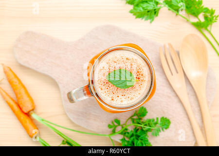 Gläser von Karottensaft mit Karotte Wurzeln auf Holz- Hintergrund. Gläser leckere frische Karottensaft. Karottensaft und Karotten. Selektiver Fokus Dept. Stockfoto