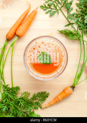 Gläser von Karottensaft mit Karotte Wurzeln auf Holz- Hintergrund. Gläser leckere frische Karottensaft. Karottensaft und Karotten. Selektiver Fokus Dept. Stockfoto