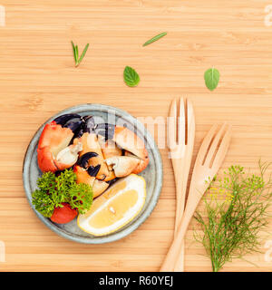 Frische gedämpfte Rote Krabben Bein in der Schüssel. Rote Krabben Bein mit Zutaten. Gedämpfte Rote Krabben Bein mit Kräutern, Fenchel, Petersilie, Rosmarin, Zitrone und Minze mit Gabel auf Holz Schneidebrett. Stockfoto