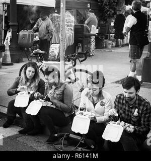 OAKLAND, CA - 6. Juni 2014: Millenials auf dem Bürgersteig bändigen Essen Street Food in monatlichen der Stadt Kunst Murmeln uptown Galerie hop sitzen. Straße Chefs. Stockfoto