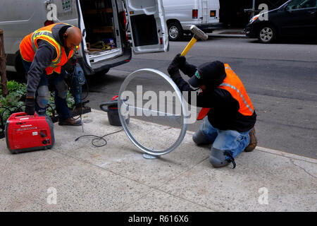 Mitarbeiter des NYC Department of Transportation installieren auf einem Bürgersteig in Midtown Manhattan, New York, New York, einen „CityRack“-Fahrradträger