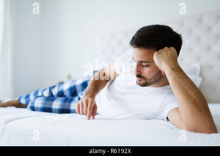 Portrait von unglücklichen Mann liegend auf Bett Stockfoto